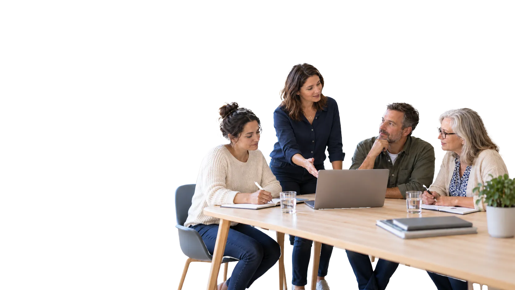 Vier Erwachsene sitzen und stehen an einem hellen Holztisch mit Laptop und besprechen sich