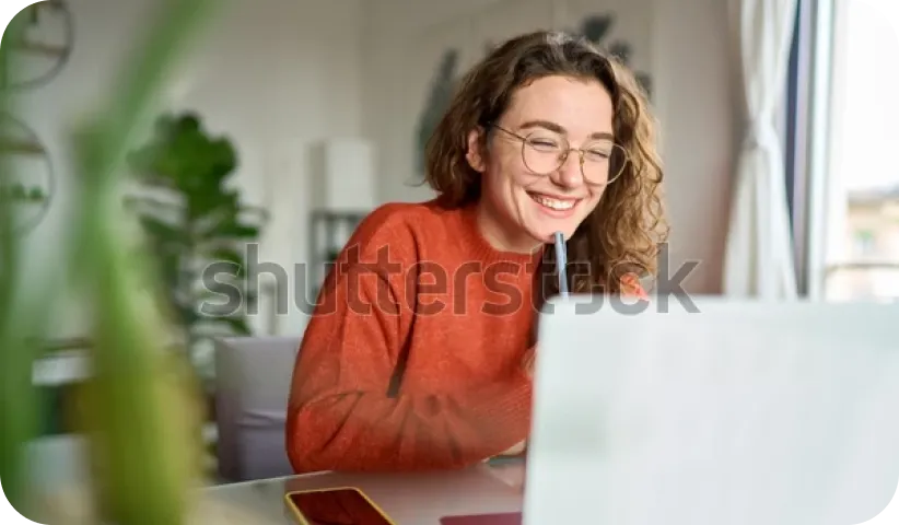 Lächelnde Frau mit Brille sitzt vor einem Laptop und nimmt an einer Online-Schulung teil
